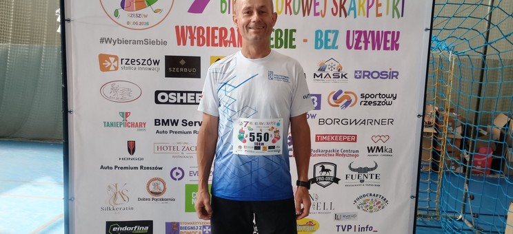 Zdjęcie przedstawia zawodnika na tle baneru biegu Kolorowa Skarpetka