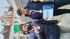 Dwóch biegaczy z medalami, a jeden trzyma puchar i dyplom