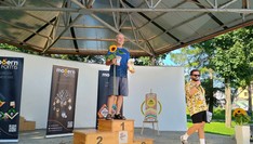 Biegacz stojący na podium, obok prowadzacy imprezę